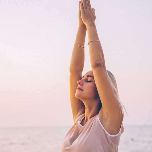 Woman feeling energized and stretching outdoors at sunrise.